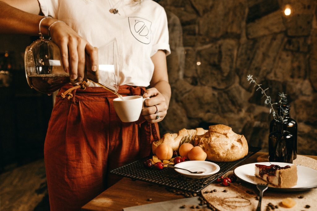 A waitress making a drink and plating up cake.